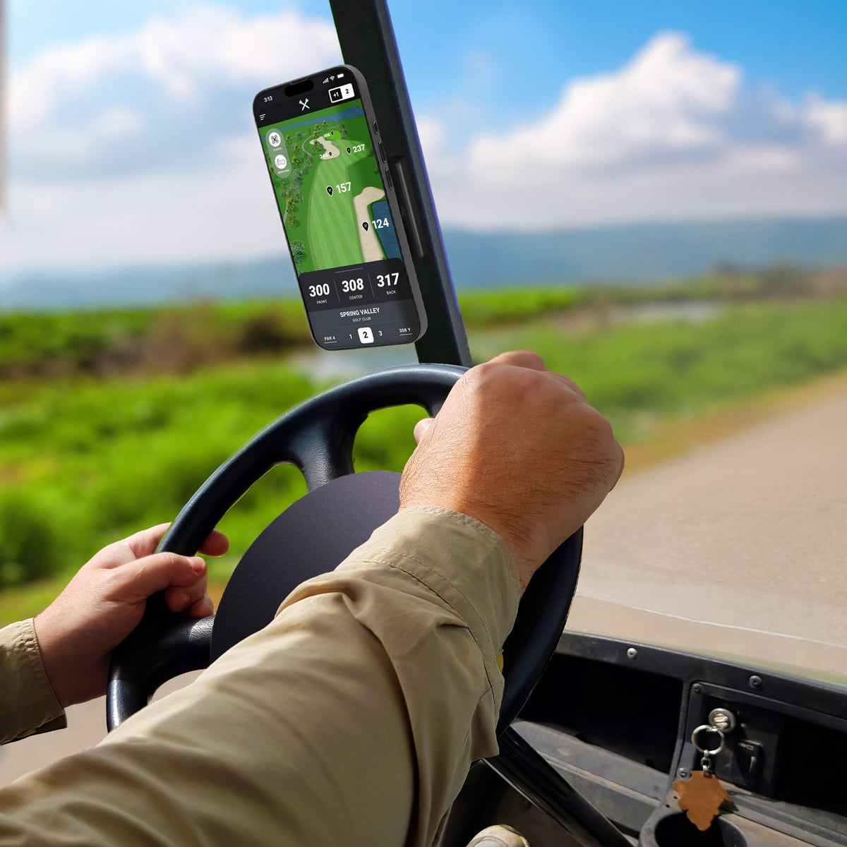 Golf cart dashboard with magnetic phone mount holding a smartphone, black plastic construction, outdoor golf course background