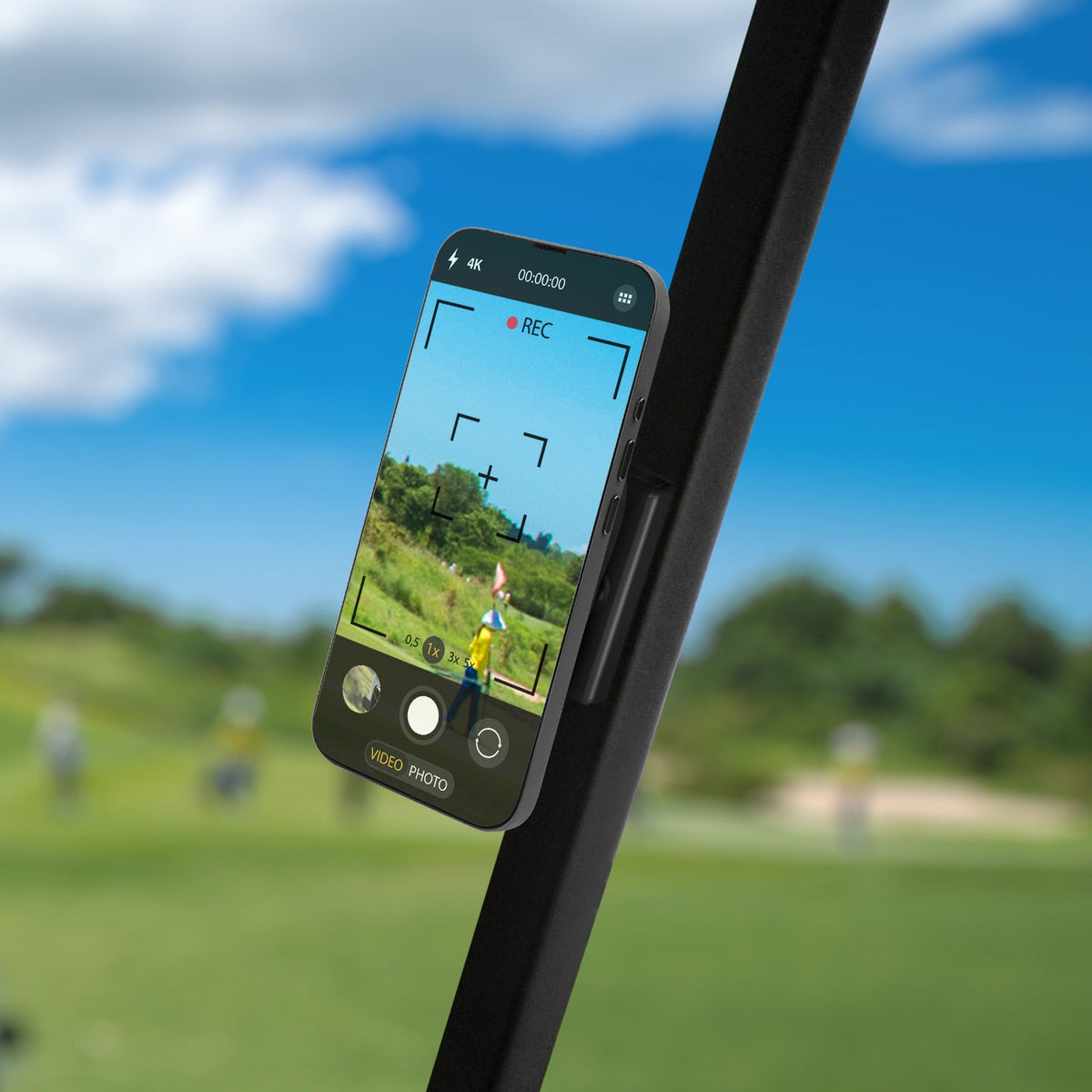 Close-up of magnetic golf cart mount on dashboard, holding a smartphone with golf course scenery, black plastic design