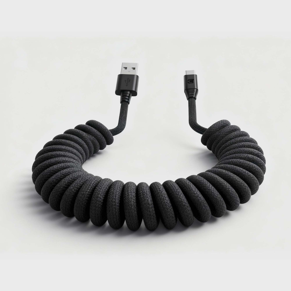 Black braided coiled USB-C to USB-A charging cable with connectors on white background, SKU: C0520-30