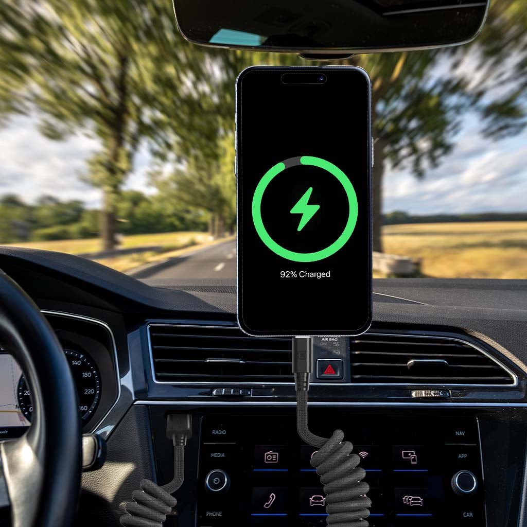 Coiled USB-C to USB-C cable charging a smartphone in a car, black braided material, magnetic connectors, 92% charged display on phone